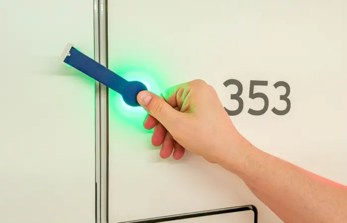 Mies näyttää RFID-ranneketta Enkoran älylokerolla Matinkylän uimahallin pukuhuoneessa